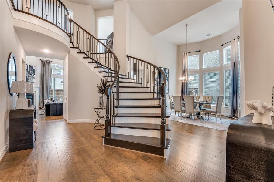 Stairs featuring a high ceiling, wood finished floors, and a chandelier