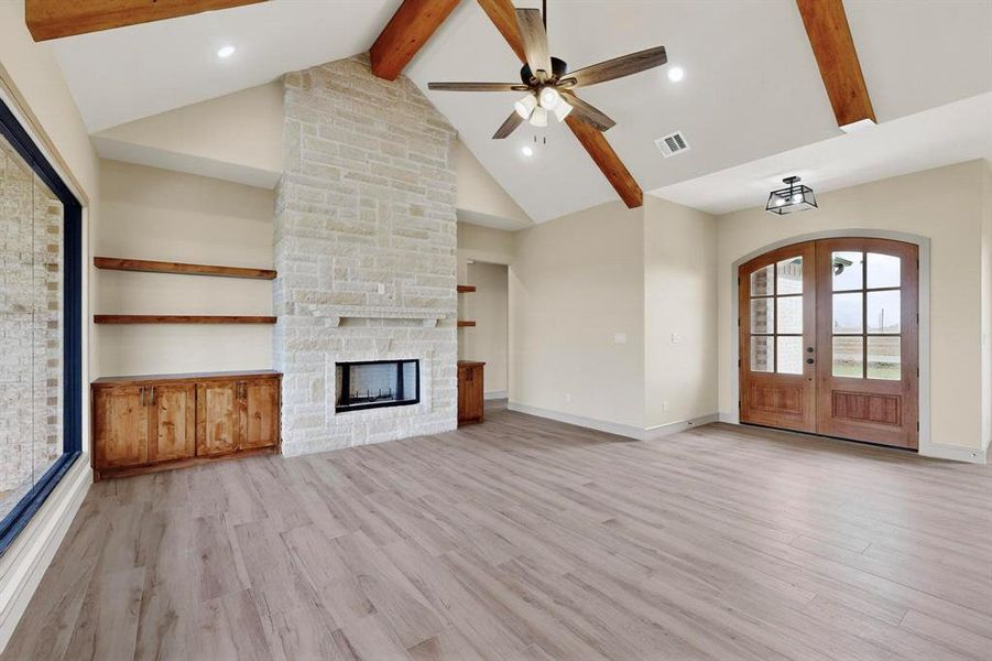 Unfurnished living room featuring beam ceiling, french doors, light wood-style flooring, recessed lighting, and high vaulted ceiling Unfurnished living room featuring beam ceiling, french doors, light wood-style flooring, recessed lighting, and high vaulted ceiling