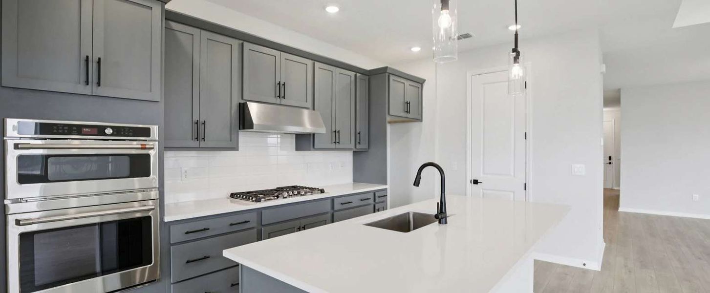 The kitchen features a stacked oven and microwave, flat top range and a vent hood the kitchen will feature AW Collection® Sapphire - Representative images and renderings are for illustrative purposes