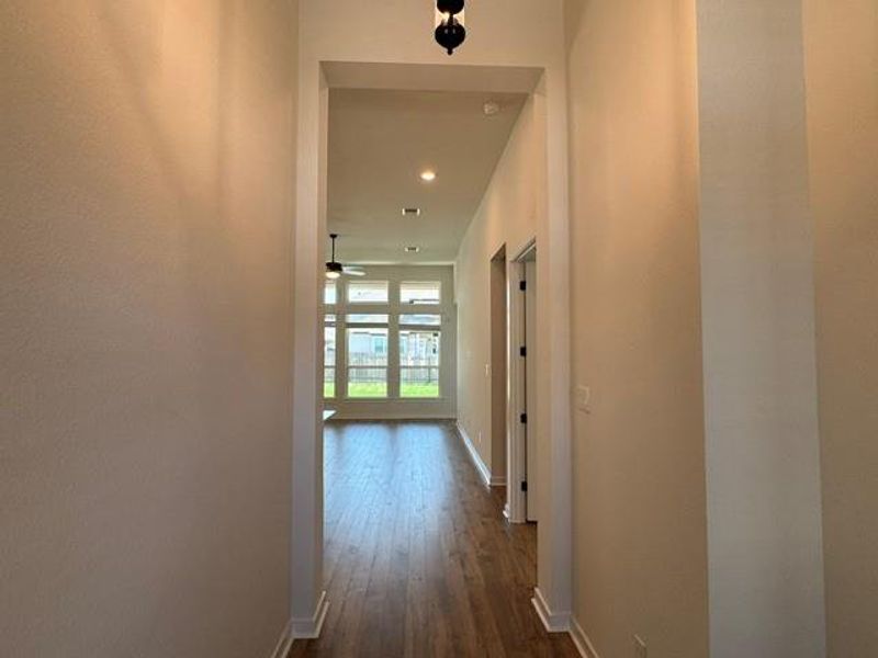A long, inviting hallway draws the eye towards a sunlit living space with ample window views.
