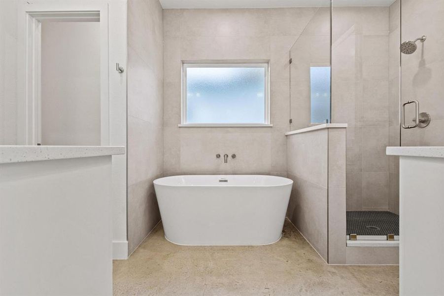 Full bathroom with a stall shower, a freestanding bath, and tile walls