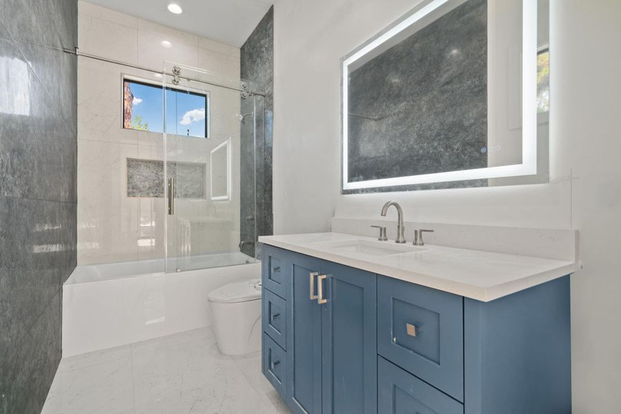 This stylish bathroom defines a clean and modern aesthetic, with a spacious vanity and elegant finishes. Bright lighting and neutral design enhance the airy feel. Tiled tub-shower feels fresh and inviting .