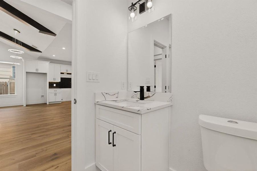 Bathroom featuring vaulted ceiling, vanity, and wood finished floors Bathroom featuring vaulted ceiling, vanity, and wood finished floors