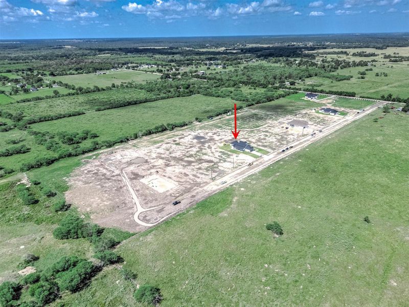 Aerial view showing the home’s location within the subdivision, surrounded by open land and spacious lots.