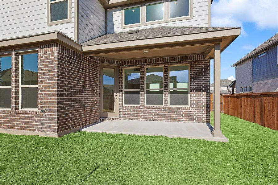 Back of house featuring brick siding, a patio area, and a shingled roof