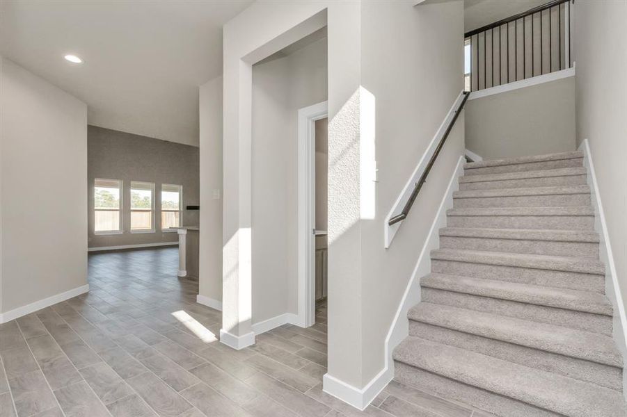 Meet the half bath and wide stair access across from the dedicated home office. Sample photo of completed home with similar floor plan. As-built interior colors and selections may vary.