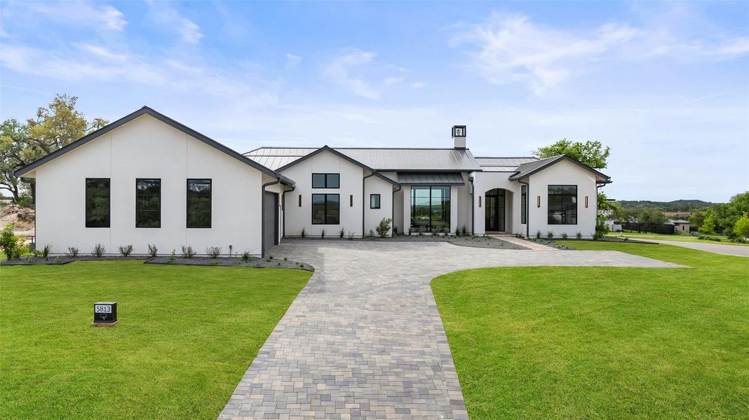 View of front of house with a standing seam roof, a chimney, metal roof, a front yard, and decorative driveway View of front of house with a standing seam roof, a chimney, metal roof, a front yard, and decorative driveway