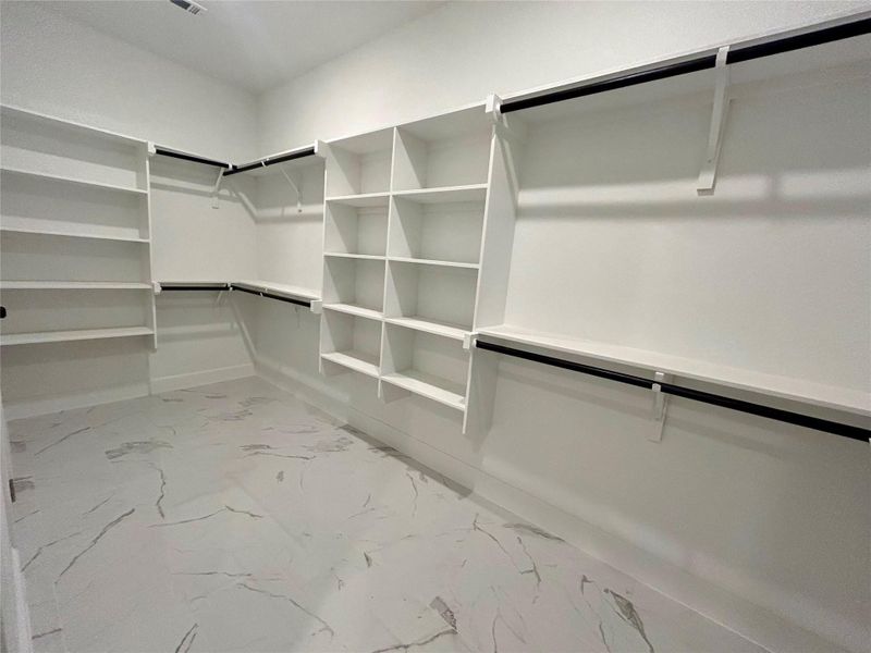 Primary bedroom walk-in closet with tiled floor.