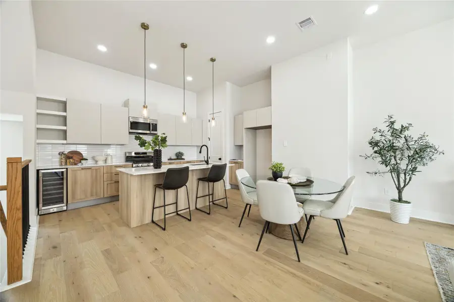 Modern kitchen with sleek cabinetry, stainless steel appliances, and a spacious island. Adjacent dining area offers ample seating, perfect for entertaining.