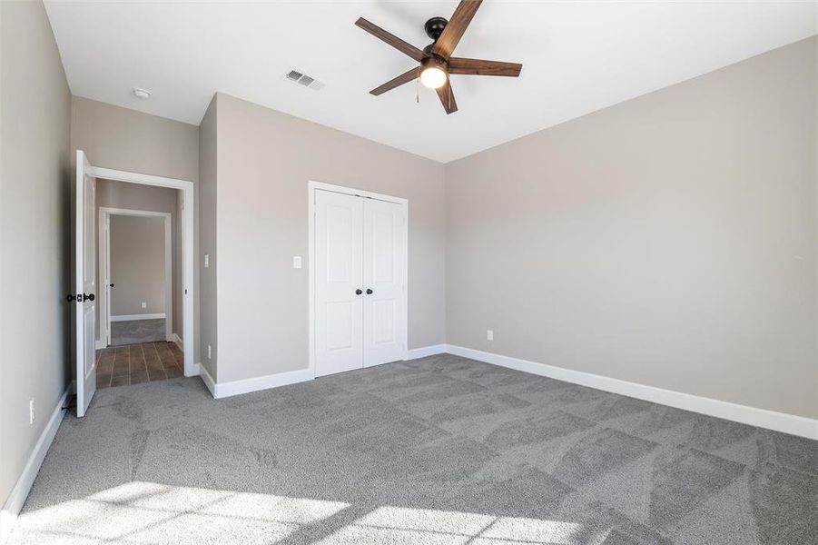 Unfurnished bedroom with carpet floors, ceiling fan, and a closet