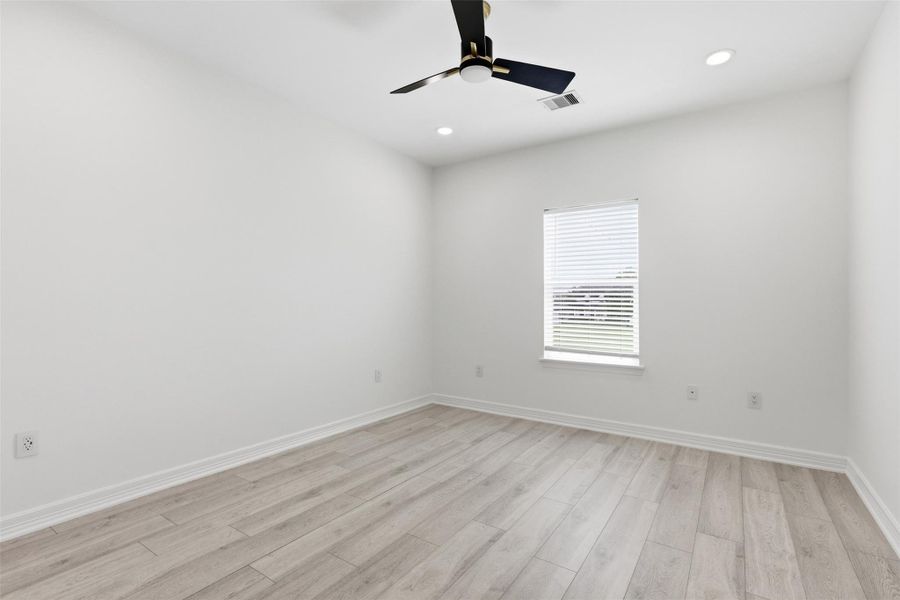 Bright second floor bedroom with ceiling fan, large window, and light wood look floors.