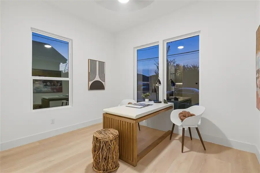 Bright room featuring two large windows, light wood-finish flooring, white walls, and a contemporary ceiling light fixture