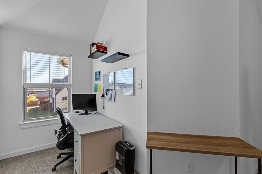 Office area with light carpet and vaulted ceiling