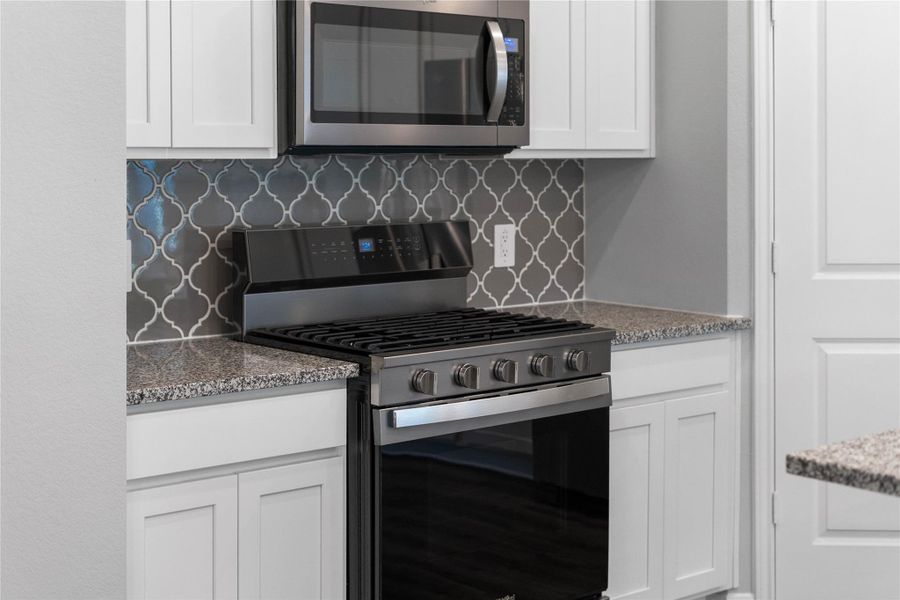 Showcased here is a Whirlpool gas range, paired with a steam microwave equipped with sensor cooking—all framed by an elegant tile backsplash. Showcased here is a Whirlpool gas range, paired with a steam microwave equipped with sensor cooking—all framed by an elegant tile backsplash.