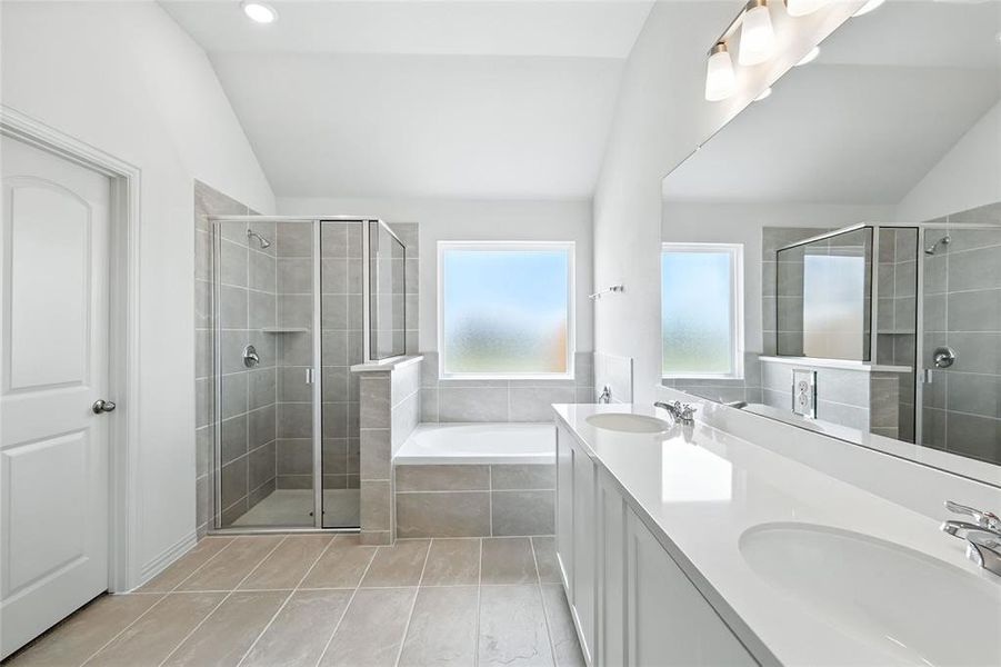 Bathroom featuring lofted ceiling, a shower stall, a garden tub, double vanity, and light tile patterned floors Bathroom featuring lofted ceiling, a shower stall, a garden tub, double vanity, and light tile patterned floors
