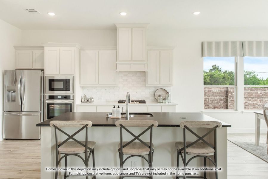 Kitchen with white cabinets, stainless steel appliances, and a dark-topped island with three bar stools