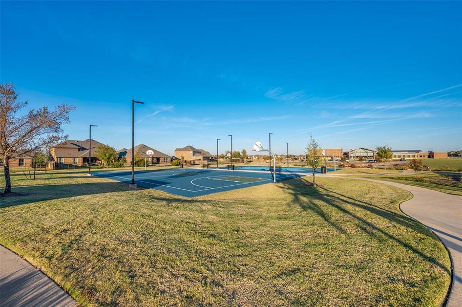View of basketball court featuring a lawn, community basketball court, and a residential view