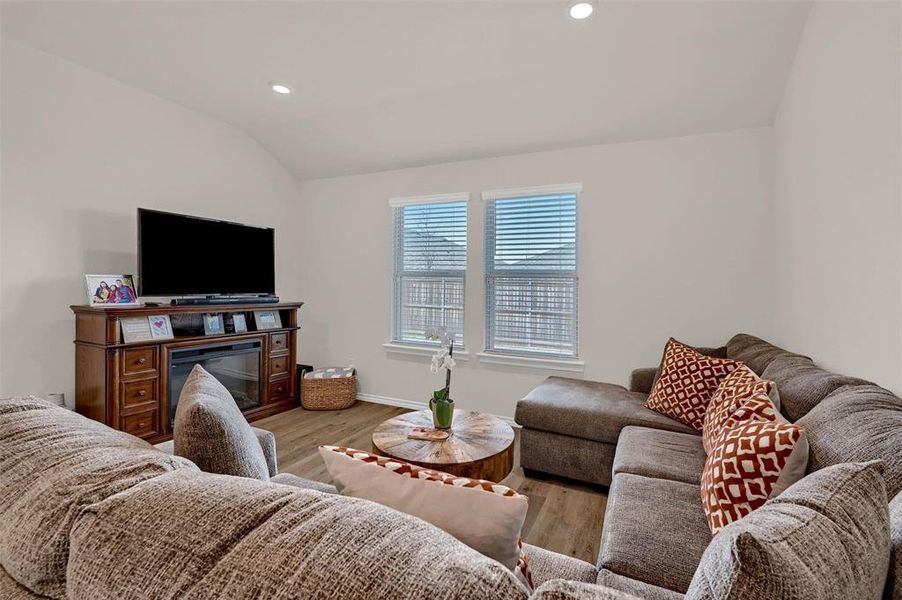 Living room featuring baseboards, vaulted ceiling, recessed lighting, and light wood-type flooring