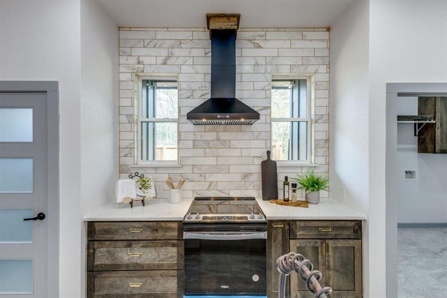 Kitchen with a wealth of natural light, electric stove, wall chimney range hood, and decorative backsplash