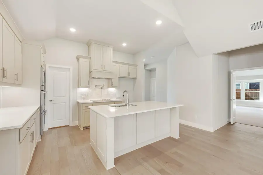 White kitchen with center island, sink, light wood floors, and tile backsplash