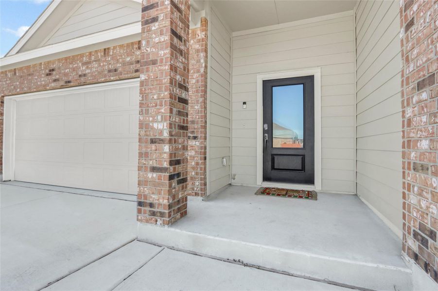Entrance to property with a garage, brick siding, and driveway