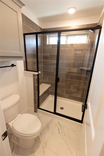 Bathroom featuring plenty of natural light, toilet, and walk in shower