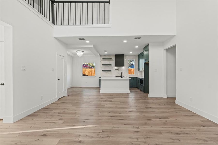 Unfurnished living room with light wood-style flooring, a high ceiling, and recessed lighting