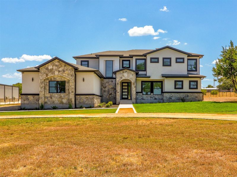 A striking modern facade blends smooth stucco, natural stone accents, and dark-trimmed windows.