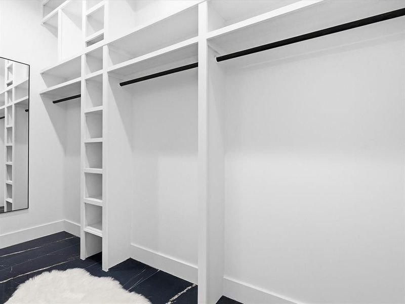 Custom closet organization system featuring white shelving and black hanging rods