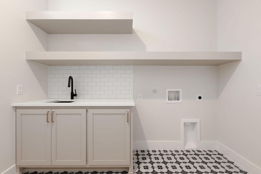 Clothes washing area featuring hookup for a washing machine, cabinet space, electric dryer hookup, a sink, and hookup for a gas dryer