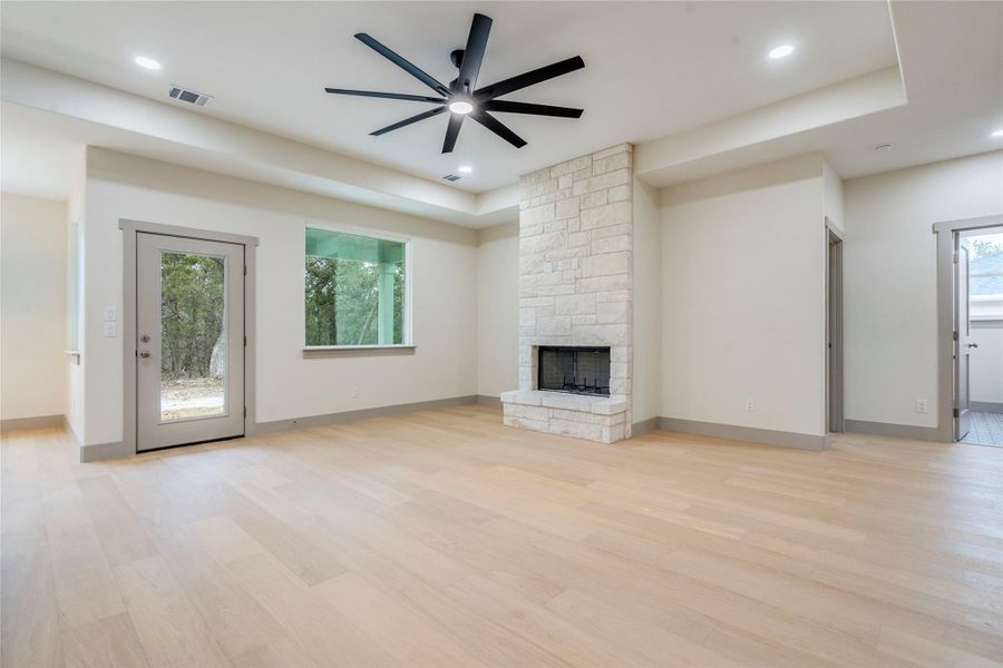 Unfurnished living room featuring ceiling fan, a fireplace, light wood-style flooring, and plenty of natural light