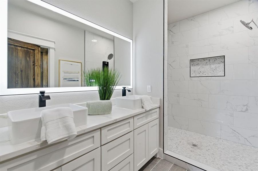 Full bathroom featuring a marble finish shower and double vanity