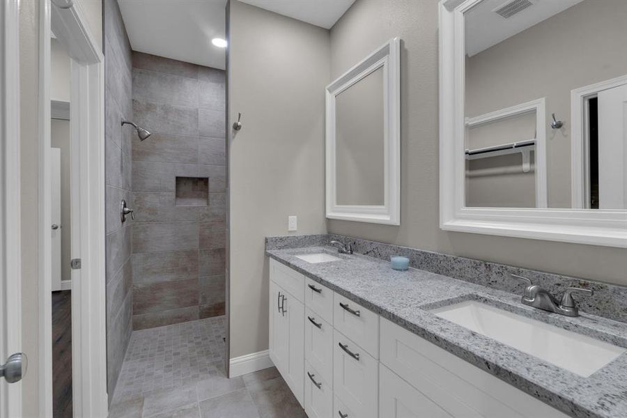 Bathroom featuring vanity, tile patterned floors, and tiled shower