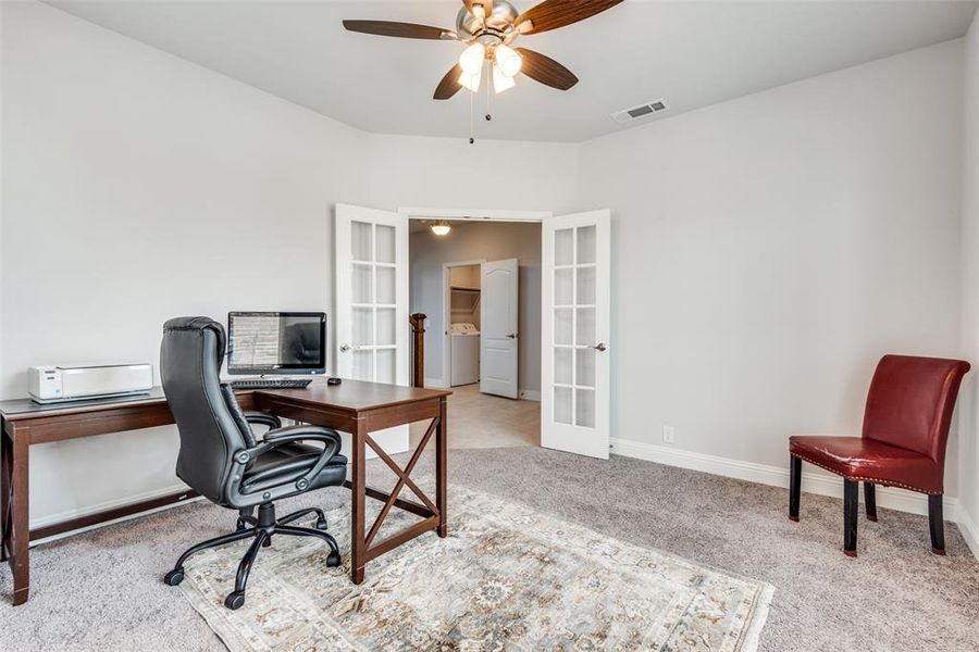 Office space featuring french doors, light colored carpet, washer / dryer, and ceiling fan