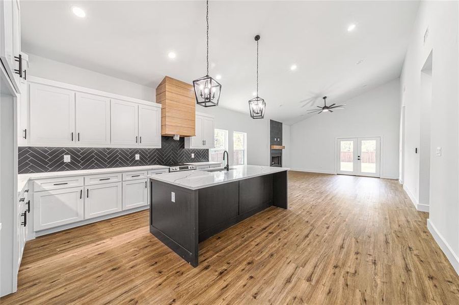 Kitchen featuring white cabinets, pendant lighting, plenty of natural light, decorative backsplash, and high vaulted ceiling