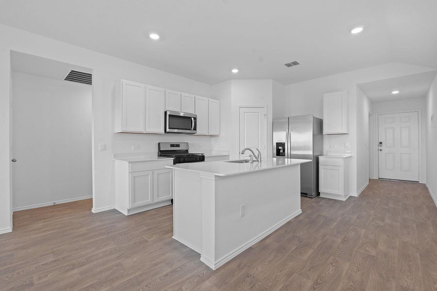 Kitchen featuring stainless steel appliances, white cabinets, recessed lighting, dark wood finished floors, and a center island with sink