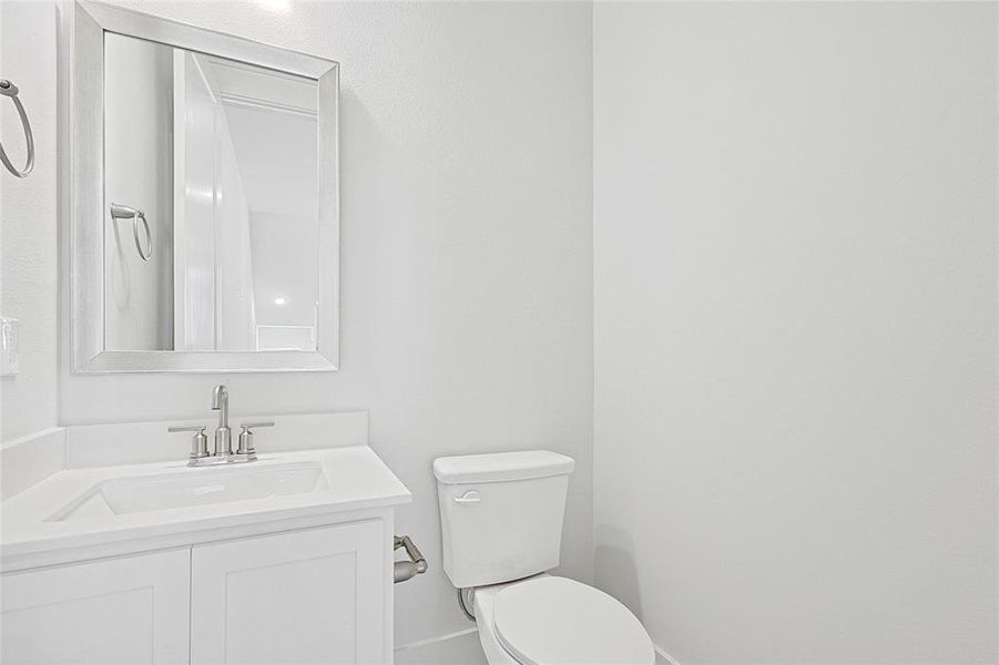 Bathroom featuring a white vanity with a rectangular sink, a polished chrome faucet, and a framed mirror