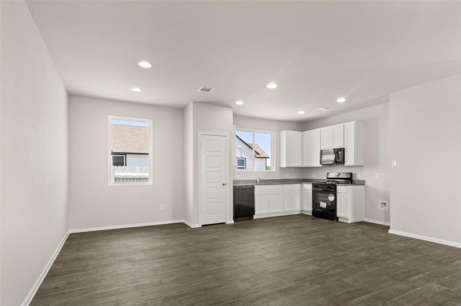 Kitchen with white cabinetry, black appliances, recessed lighting, and dark wood-type flooring Kitchen with white cabinetry, black appliances, recessed lighting, and dark wood-type flooring