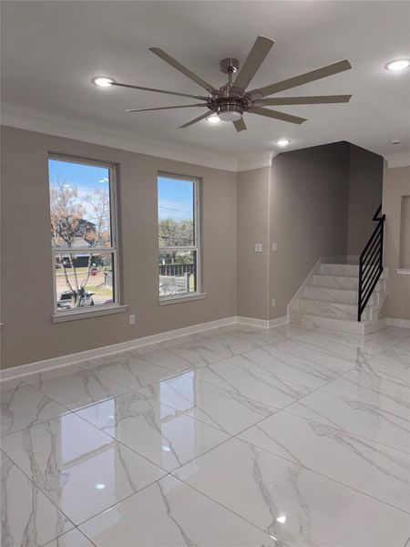 Bright and modern living space featuring sleek marble flooring, large windows for natural light, and a contemporary ceiling fan. The staircase with elegant railing adds a stylish touch. Bright and modern living space featuring sleek marble flooring, large windows for natural light, and a contemporary ceiling fan. The staircase with elegant railing adds a stylish touch.
