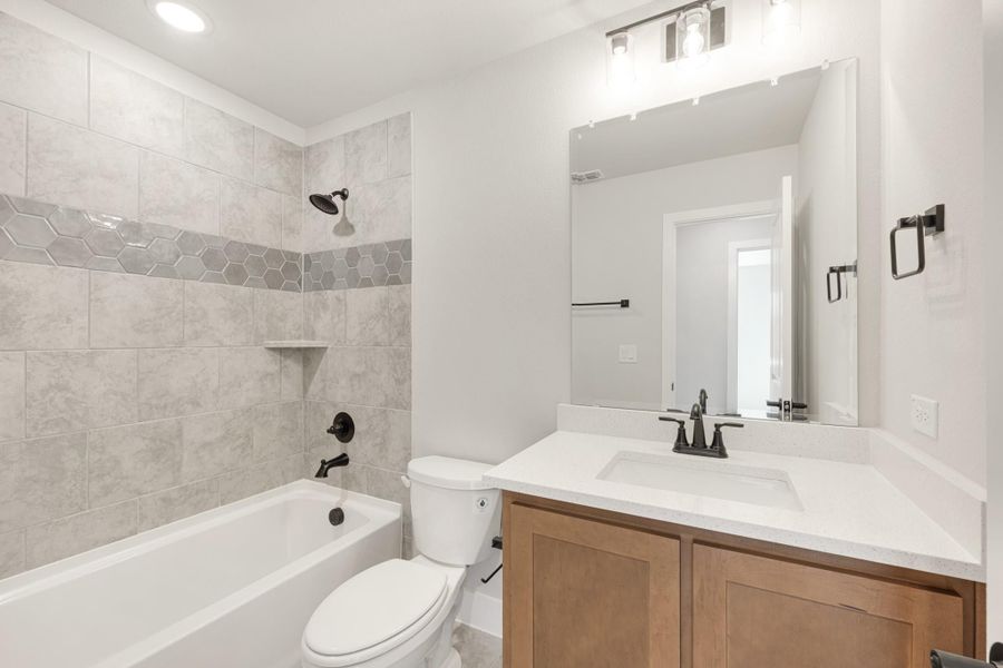 Bathroom with tiled tub-shower combo, wood vanity with white countertop, and black fixtures Bathroom with tiled tub-shower combo, wood vanity with white countertop, and black fixtures