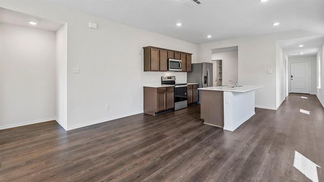 Kitchen with stainless steel appliances, a center island with sink, recessed lighting, dark wood-style flooring, and dark wood finish cabinetry Kitchen with stainless steel appliances, a center island with sink, recessed lighting, dark wood-style flooring, and dark wood finish cabinetry