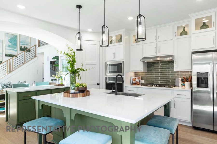 Kitchen featuring stainless steel fridge, a sink, gas stovetop, under cabinet range hood, and light wood-type flooring Kitchen featuring stainless steel fridge, a sink, gas stovetop, under cabinet range hood, and light wood-type flooring