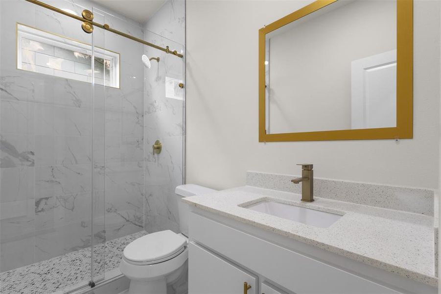 Bathroom featuring a glass-enclosed shower with gold-toned fixtures, a window, and marble-look wall tiles