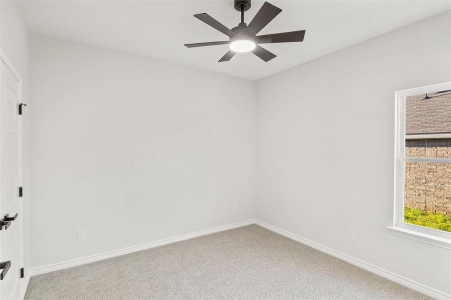 Carpeted empty room with baseboards and a ceiling fan