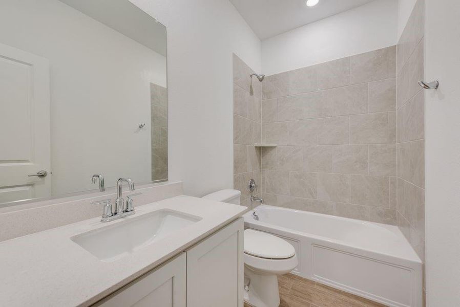 Full bathroom with vanity, tiled shower / bath combo, and toilet