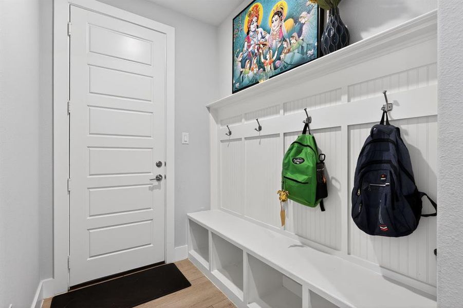 Entryway featuring a white paneled door, light-colored flooring, and a white built-in storage bench with hooks