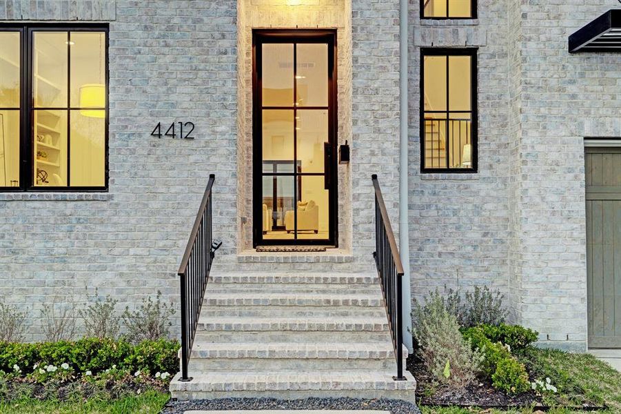 A commanding entrance, framed by a custom-designed glass front door adorned with iron accents, welcomes residents and guests alike.