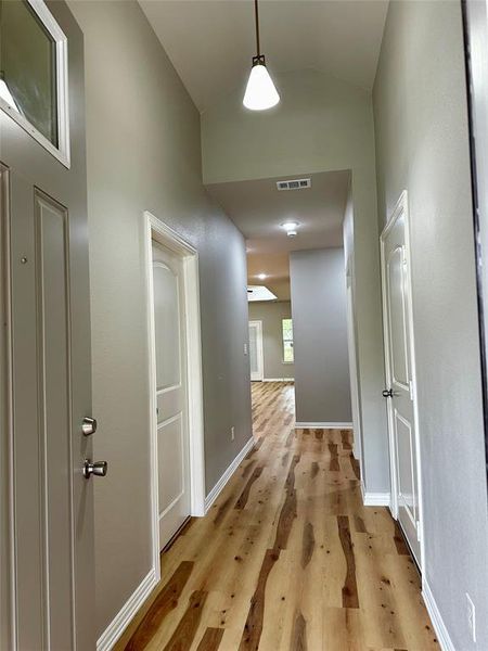 Hall with light wood-type flooring and lofted ceiling