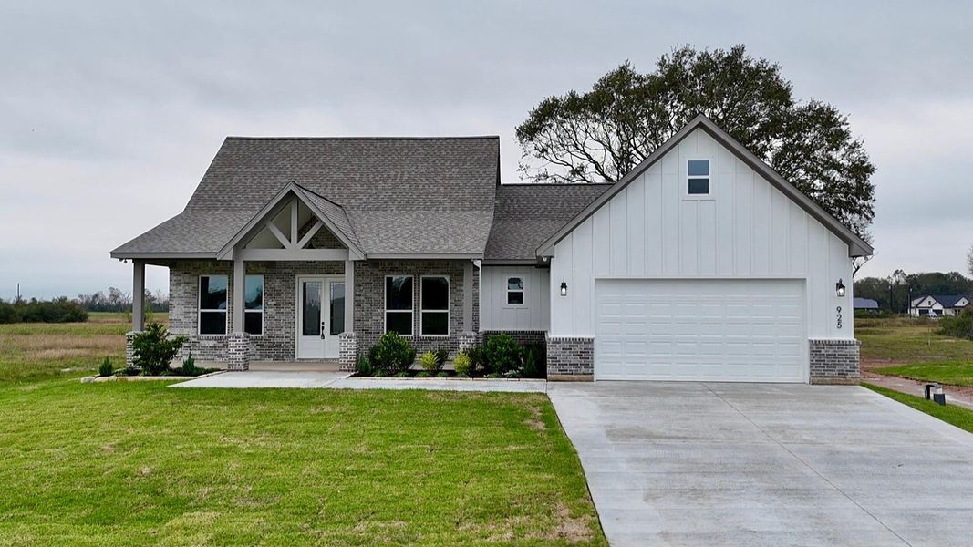 This charming home features a modern farmhouse design with a gabled roof and a welcoming front porch. It includes a two-car garage, a clean white exterior with brick accents, and is set in a spacious, grassy yard. Perfect for a peaceful, suburban lifestyle.