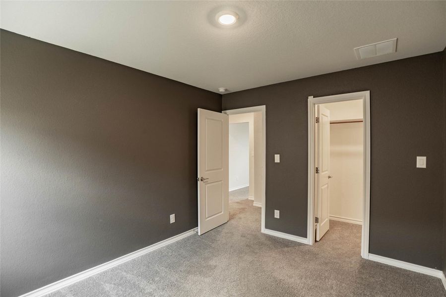 Unfurnished bedroom featuring a spacious closet and carpet Unfurnished bedroom featuring a spacious closet and carpet